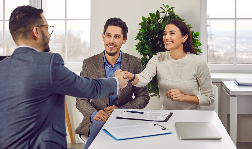 Happy customers meeting with a real estate agent in an office.