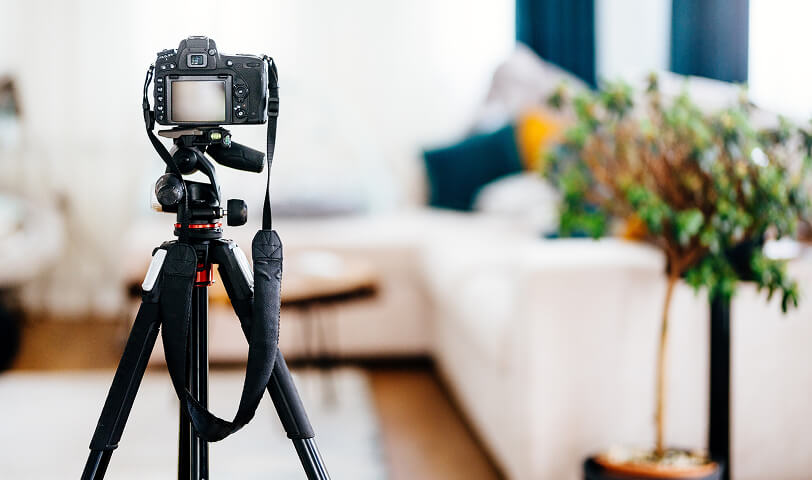 Camera mounted on a tripod capturing photos of a property.