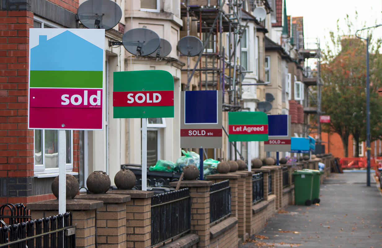 Street lined with houses displaying sold and let-agreed signs.